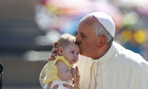 Pope Francis kisses a baby as he arrives to lead the weekly audience in Saint Peter's Square at the Vatican. (Stefano Rellandini/Reuters photo)