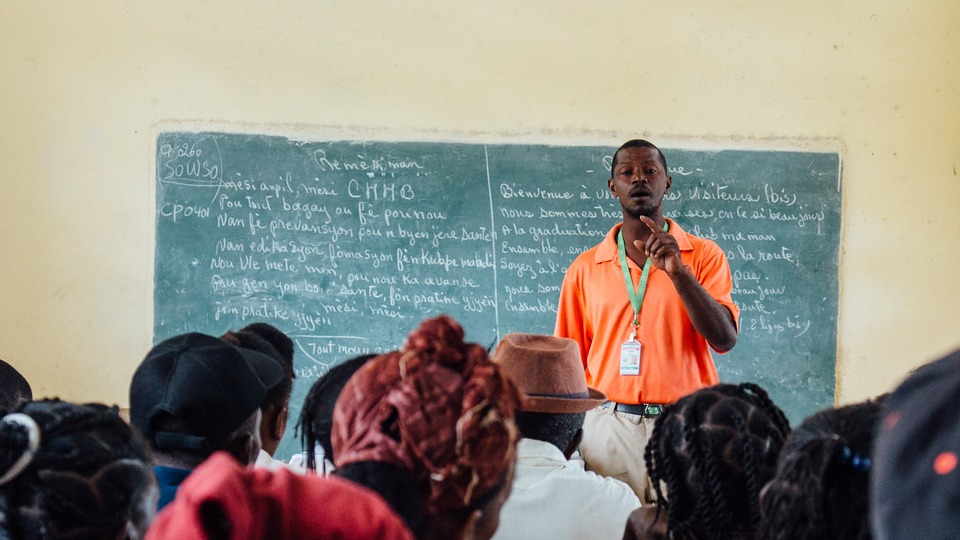 Community Health Agent, Guibert Ramilus, leads a community health meeting in Cotes-de-Fer, Haiti, teaching mothers about the health benefits of giving iron to their children.