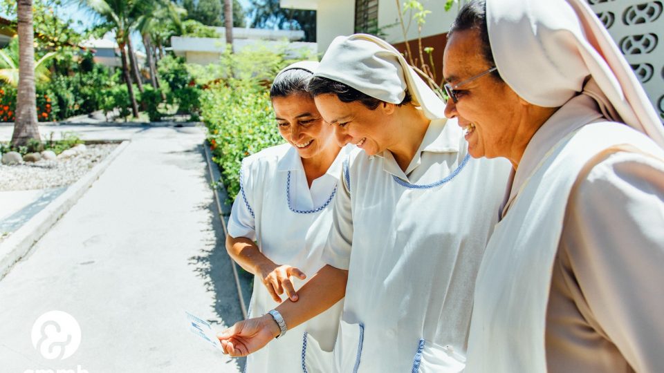 Three sisters look at a picture in Haiti. Weekly reflection sign up