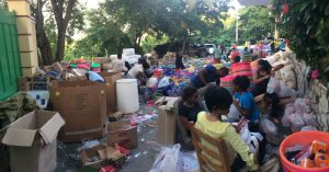 lots of people items like rice, buckets, hygiene being packaged for hurricane victims