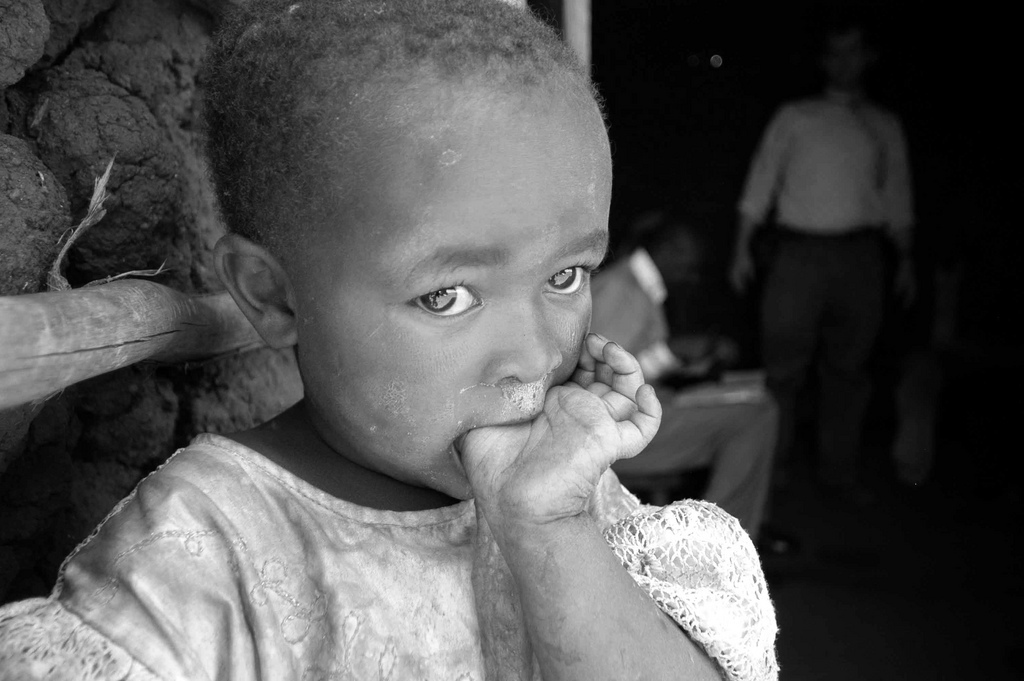 Kenyan child with her thumb in her mouth black and white hungry