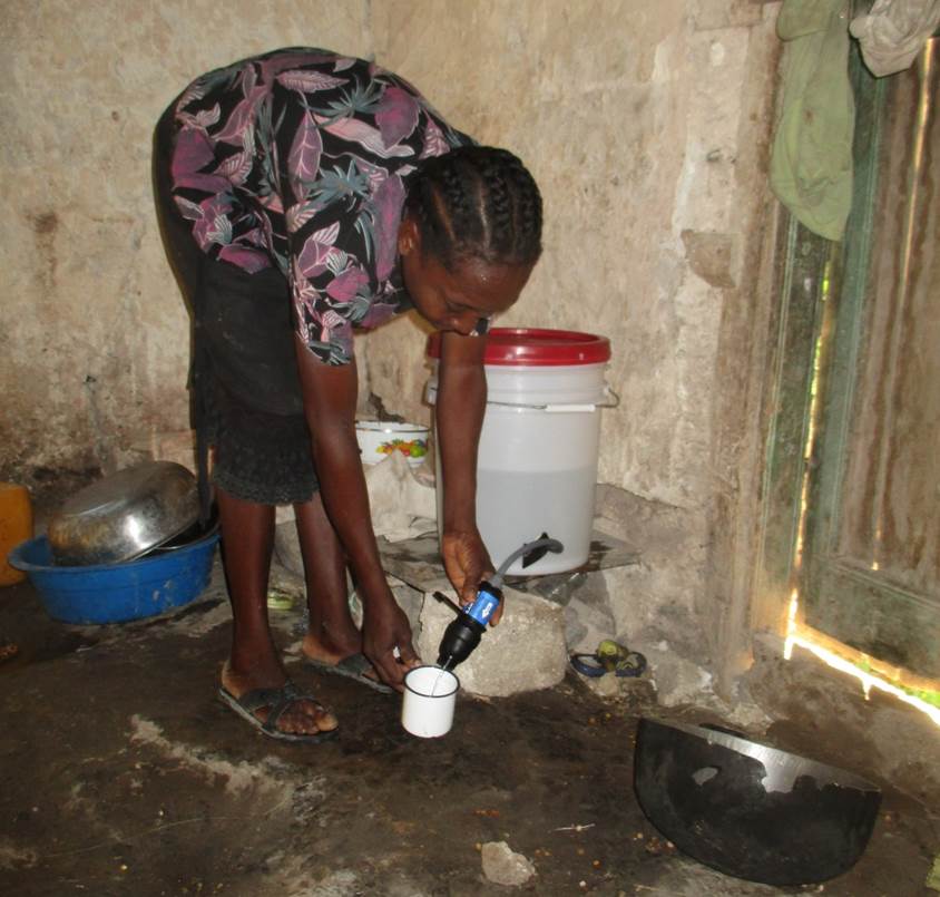 A recipient of a water filtration system in Côtes-de-Fer uses it for the first time after completing training.
