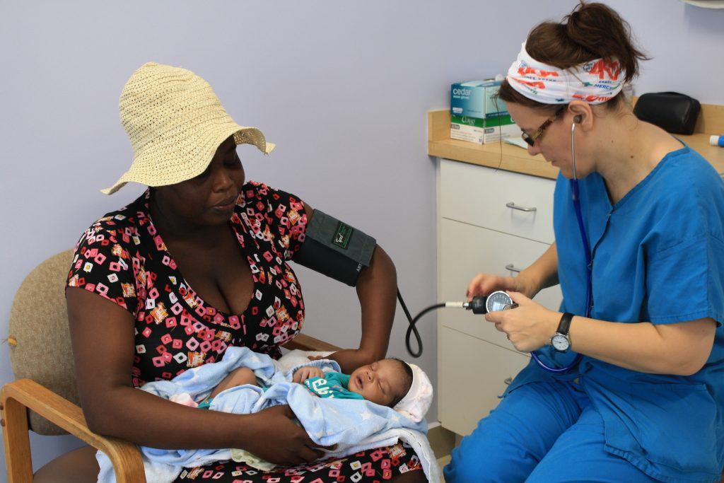 Mercy Health mission team member treating a mother and her baby in Cotes-de-Fer, Haiti