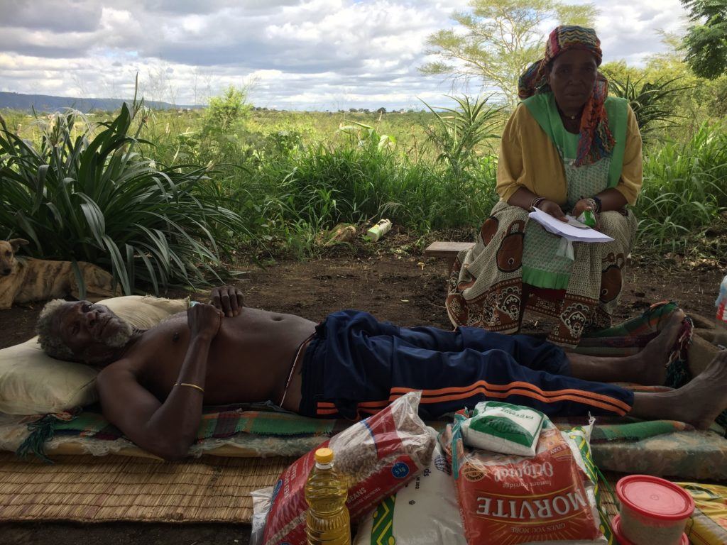 A eSwatini man lies on a reed mat receiving home based care.
