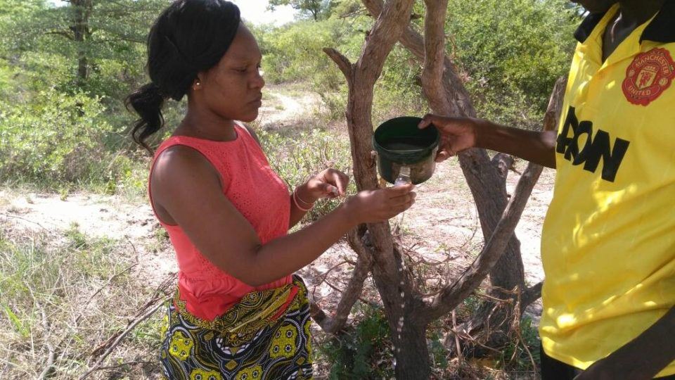Erica (left) and a WASH Champion Litebelele (right) collect water for testing from the main source used by populations in Likatalelo village.