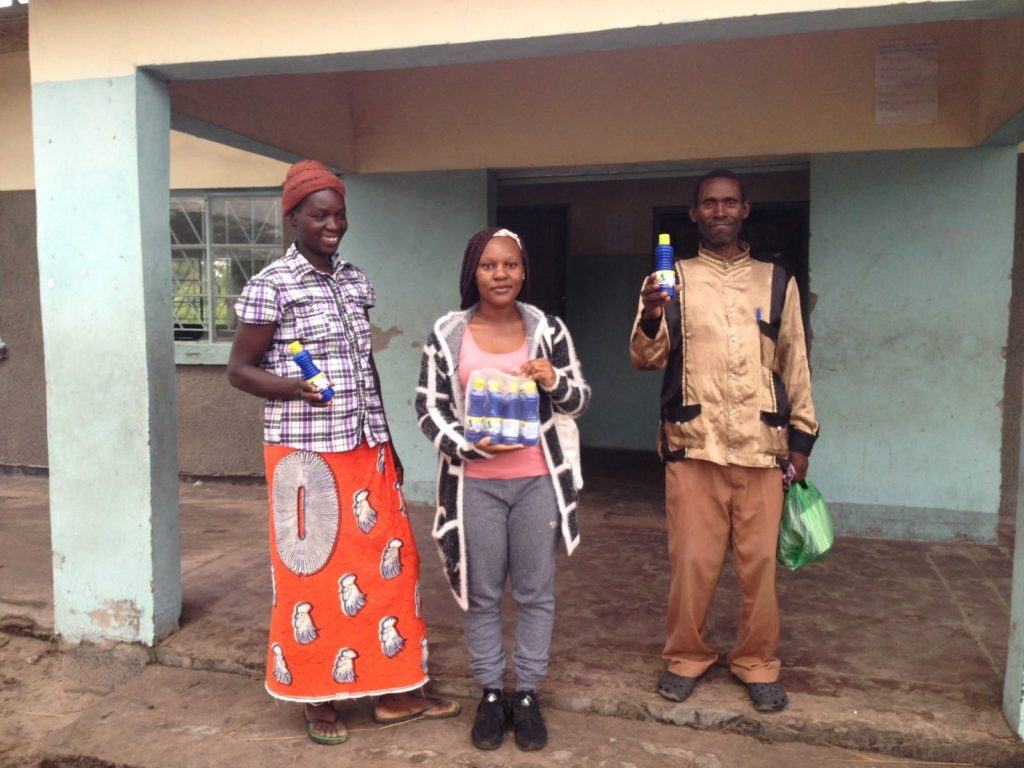 Fig: Erica CMMB Volunteer (middle) stands with community members who procured chlorine for treating water in their homes.