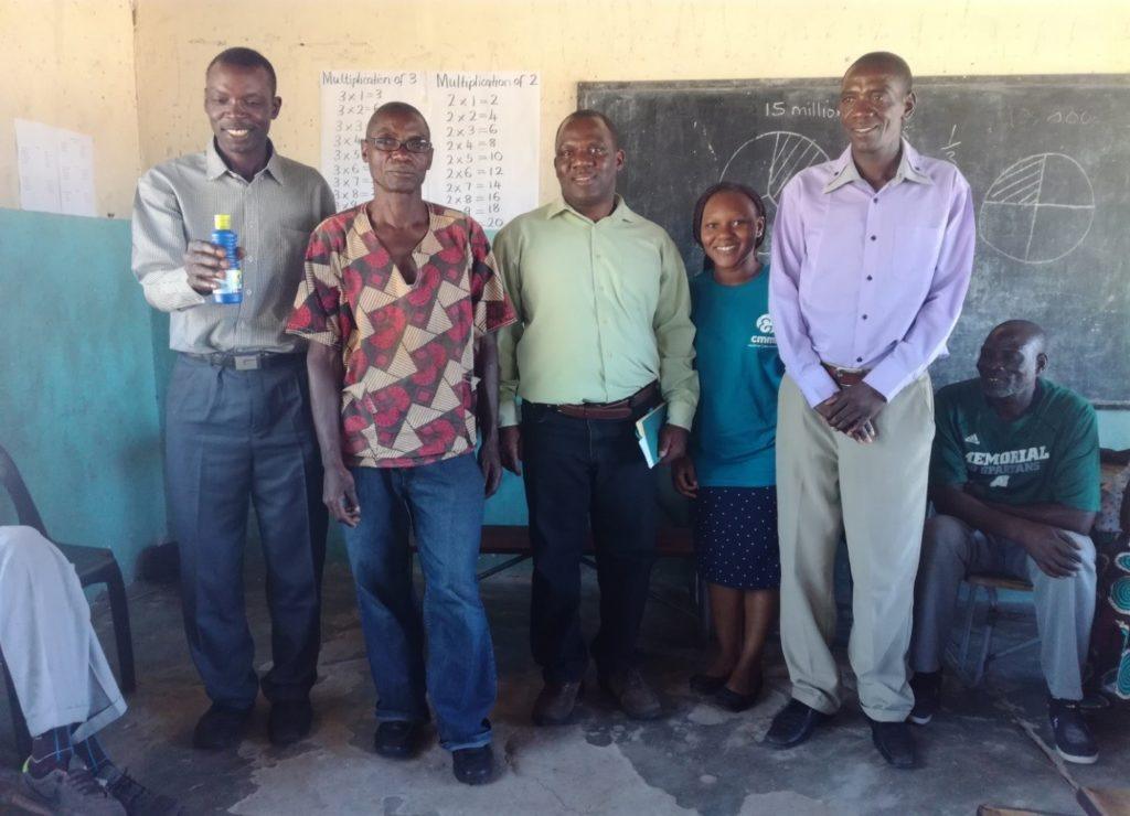 From left to right : Induna Silalo holding a chlorine bottle in  a community meeting, Mr Brian Zuze a WASH Champion, Mr Richard Shimwala CMMB CHAMPs co-ordinator,  Erica CMMB volunteer and Mr Litebelele Kekelwa a WASH Champion during a Chlorine sensitization meeting in Simungoma