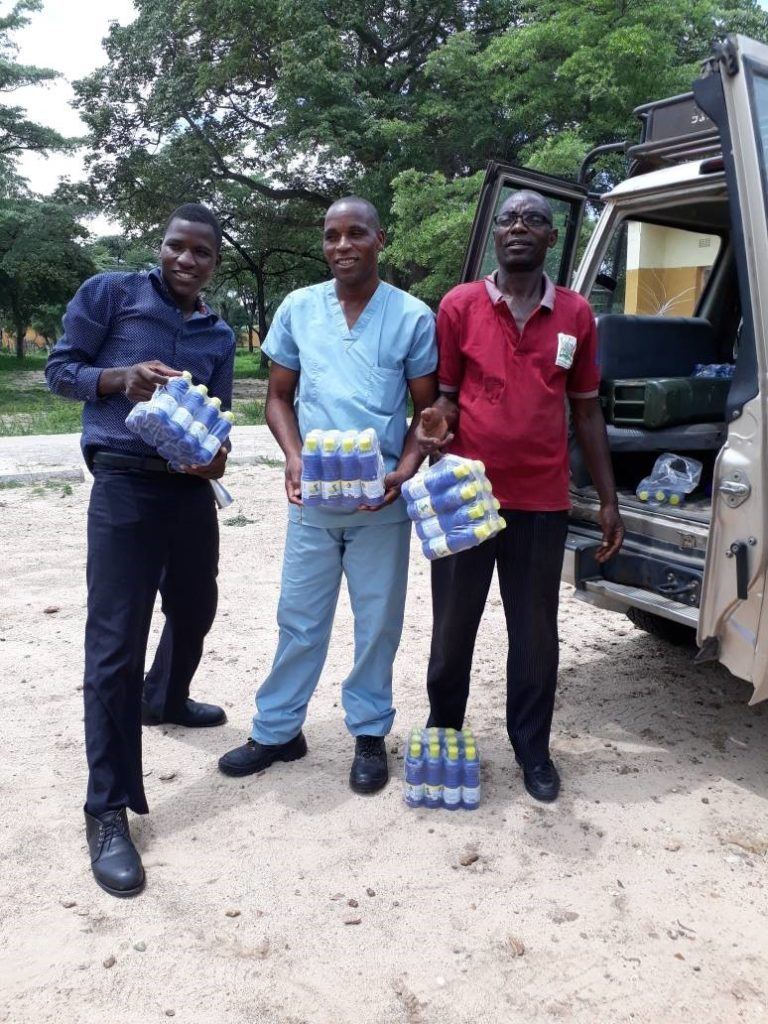 Fig: Nurse in Charge at Matoya rural Health centre (middle) stands with assistant (left) and WASH Champion (right) as they receive the chlorine bottles delivered by CMMB in their community.