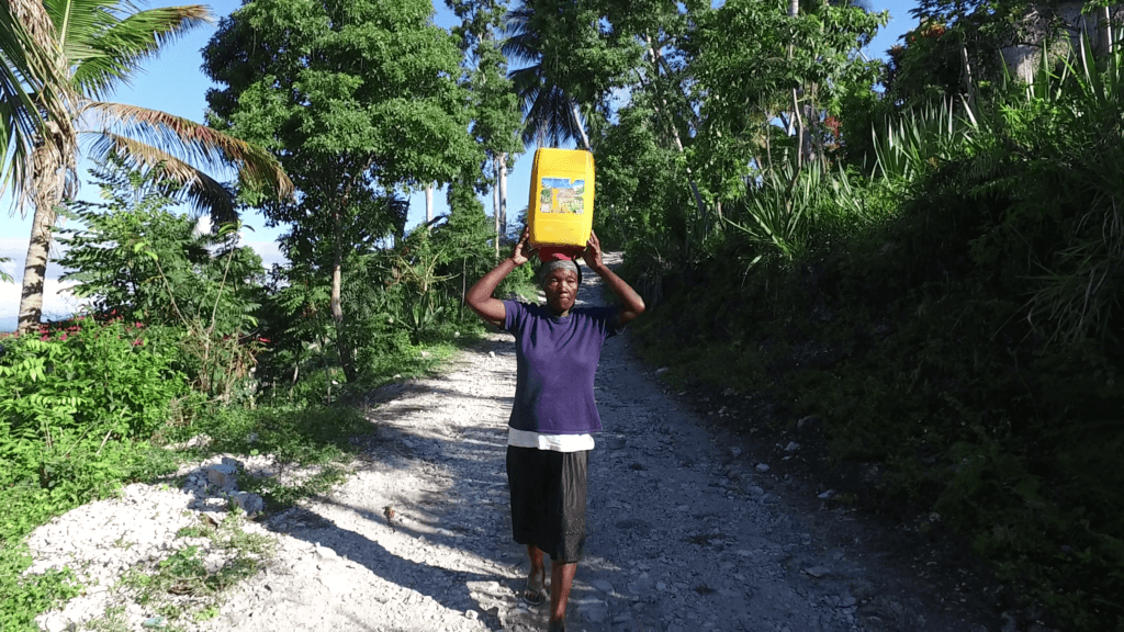 Akianne, Elderly Woman Carrying Water