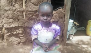 Lilian, 2 years old, standing outside her home