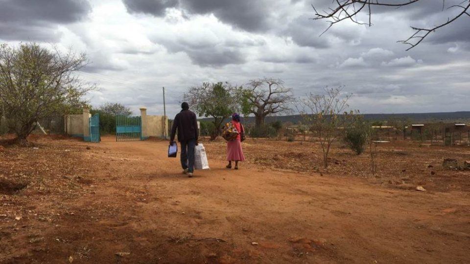 Photo of two people walking on a dirt road in Kenya