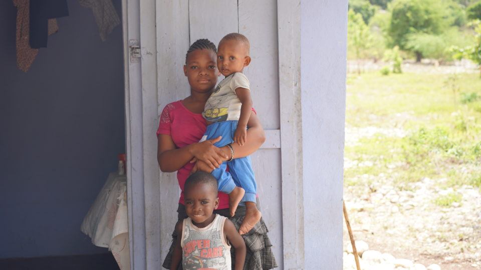 Coulins held by his mom and with his older brother Jeffrey, outside of their home in Haiti.