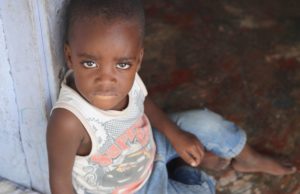 Jeffrey sitting in the doorway of his home in Haiti. He needs an Angel Investor for food and water.