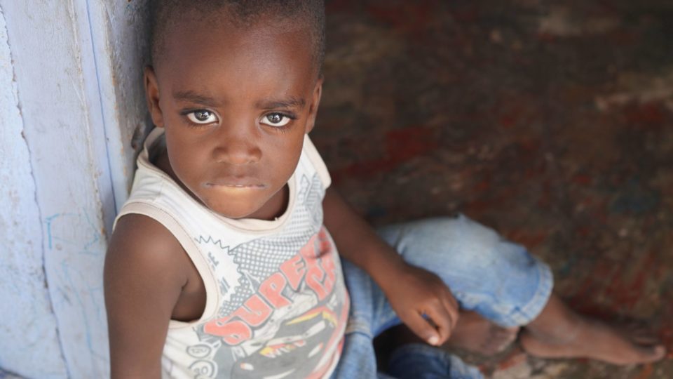 Jeffrey sitting in the doorway of his home in Haiti. He needs an Angel Investor for food and water.