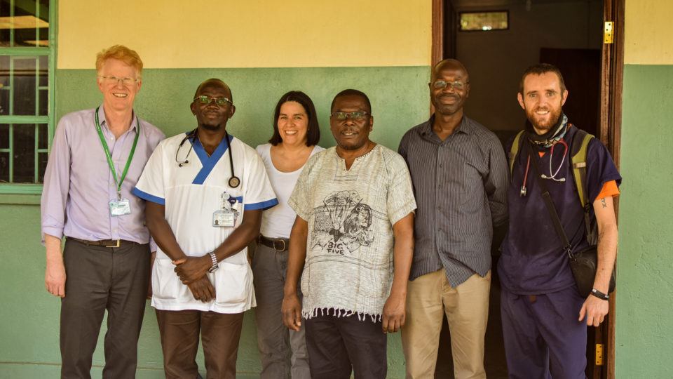 Matthew, some visiting cmmb staff, and workers standing outside the hospital.