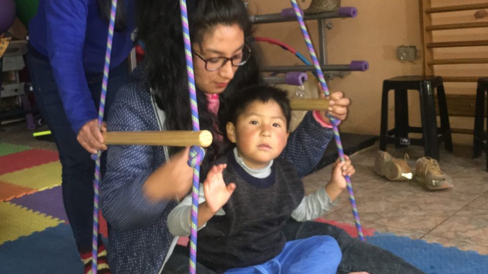 Milan on a swing for a therapy session with therapists Lorelei and Luz.