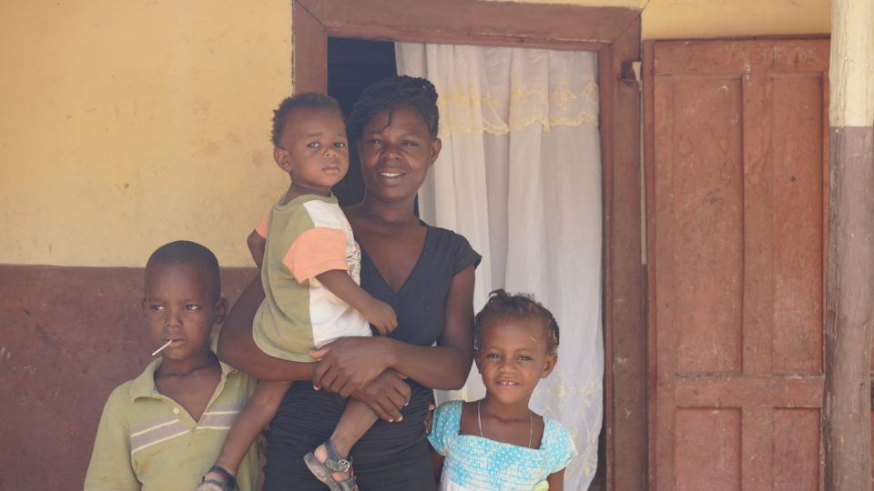 Nailine standing with her family in front of their home.