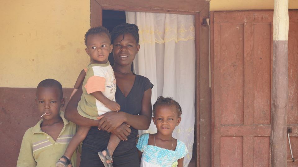 Schneider standing with his family in front of their home in Haiti.
