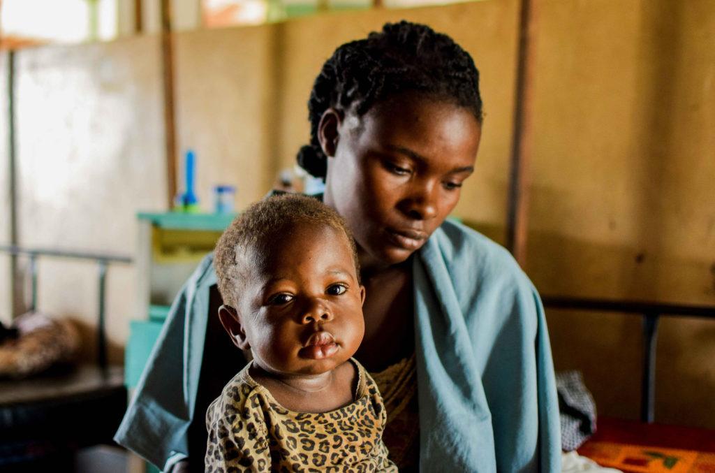 A woman at St. Theresa Hospital with her baby, looking a little downcast.