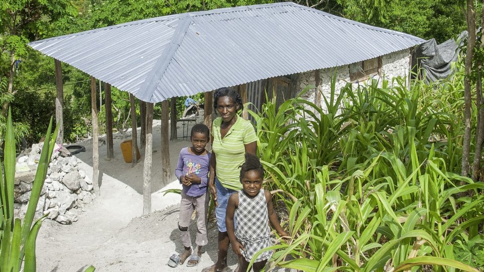 Genica in front of her home with her mother and brother