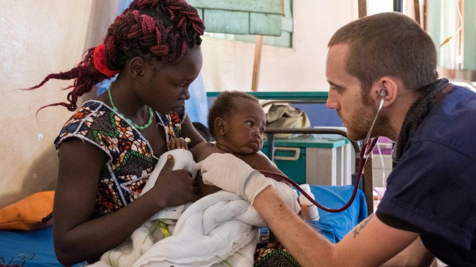 Dr. Matt checks on a baby it's mother's arsm
