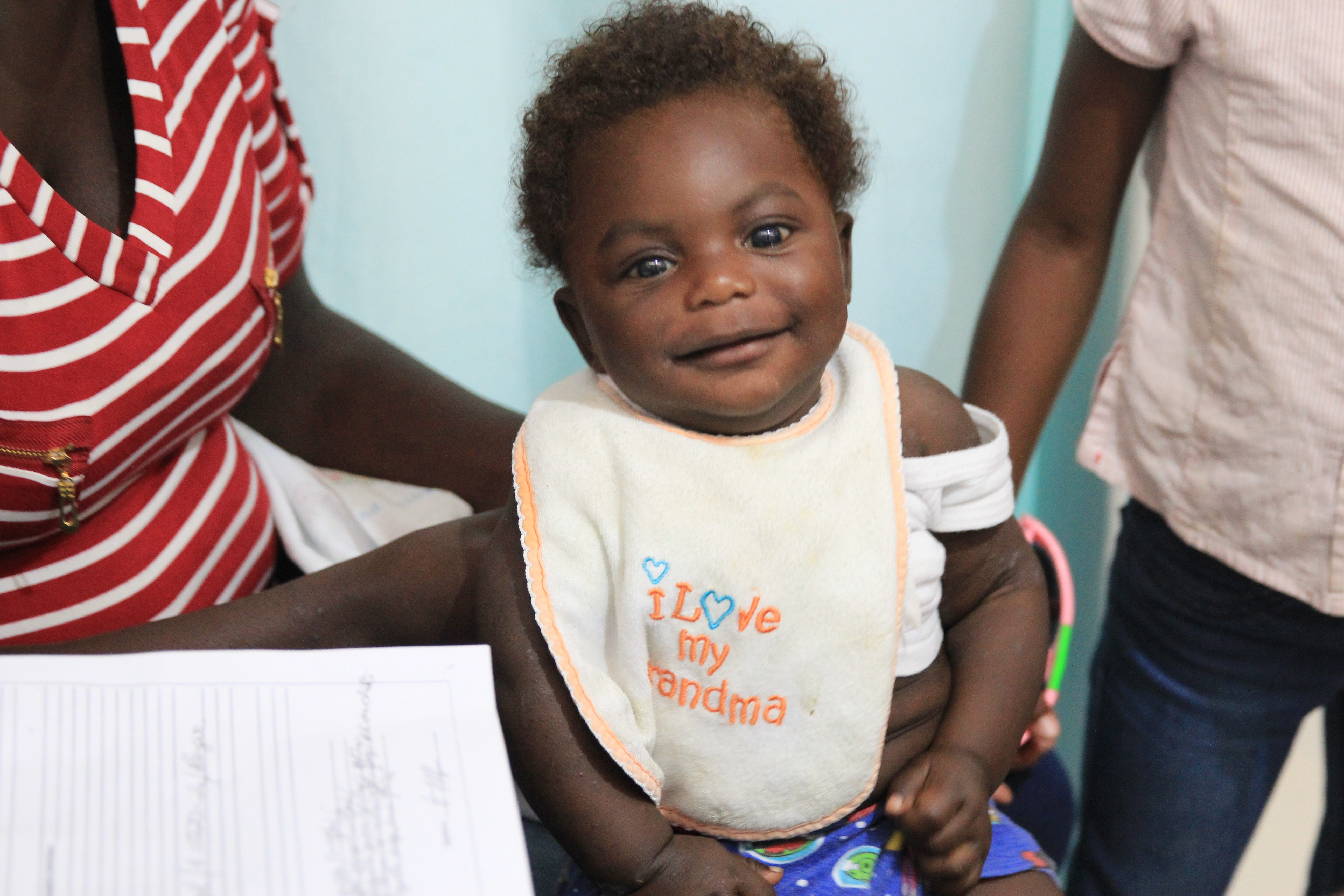Baby Daison smiles in his mom's lap at the clinic during a check-up