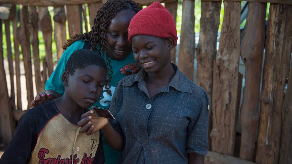 Catherine showing two community children a polaroid photo