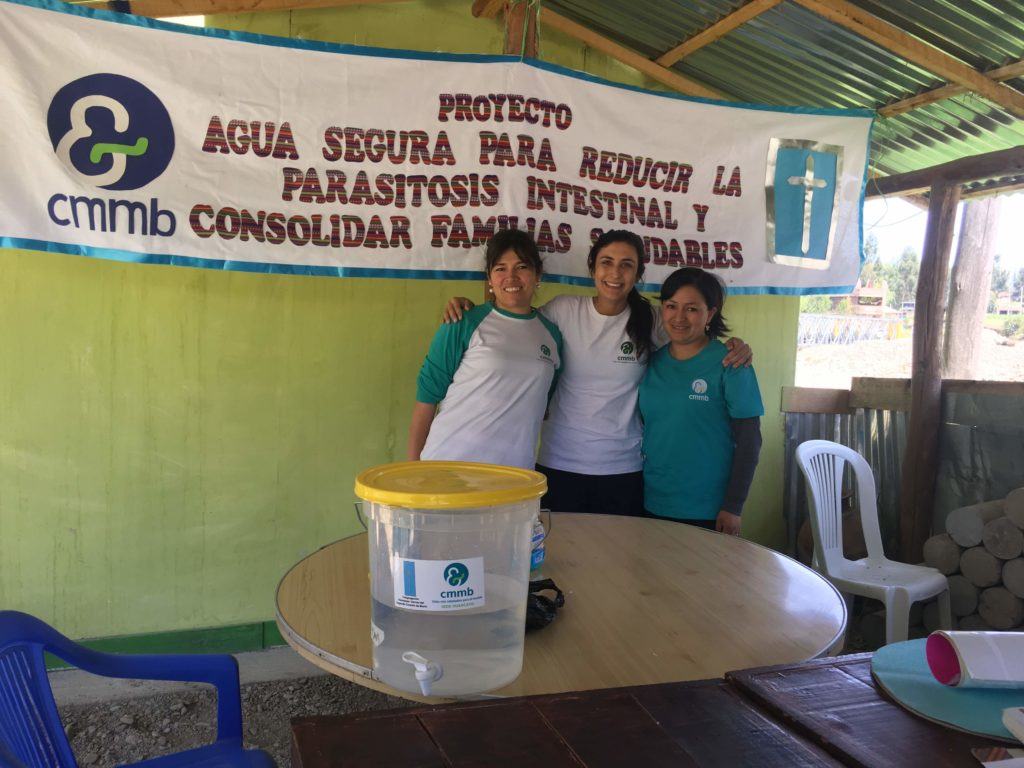 Jolynn and two CMMB Peru staff members prepare for a WASH presentation. They stand in front of a CMMB banner 