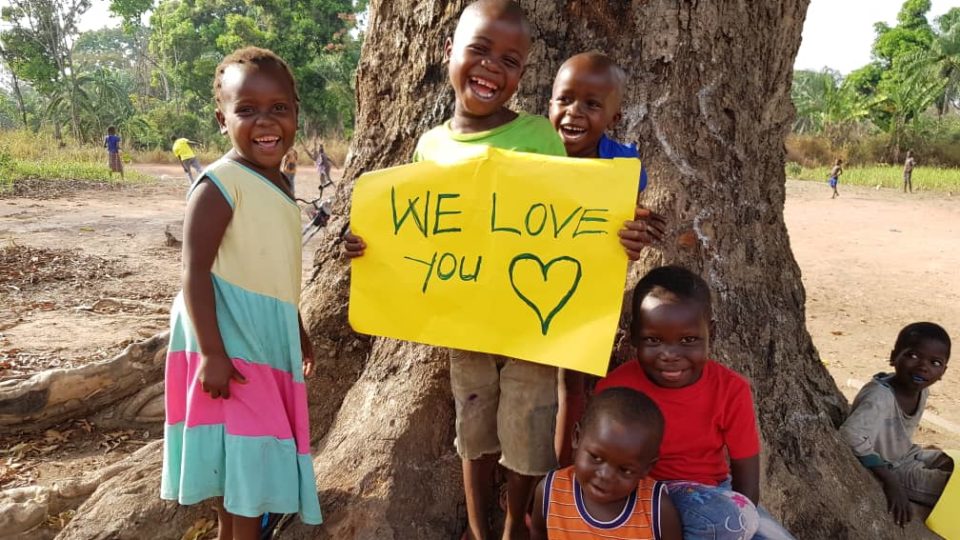South Sudanese boy with multiple friend holding Valentines Day sign