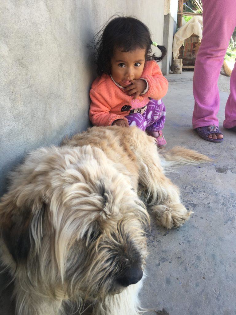 Mia, a young girl served in Peru, sitting with a puppy 