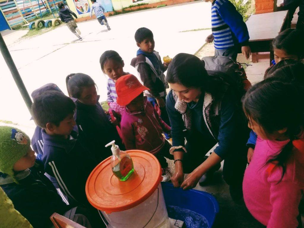 Vollunteer Jolynn demonstrating how to properly wash hands to young children in Peru