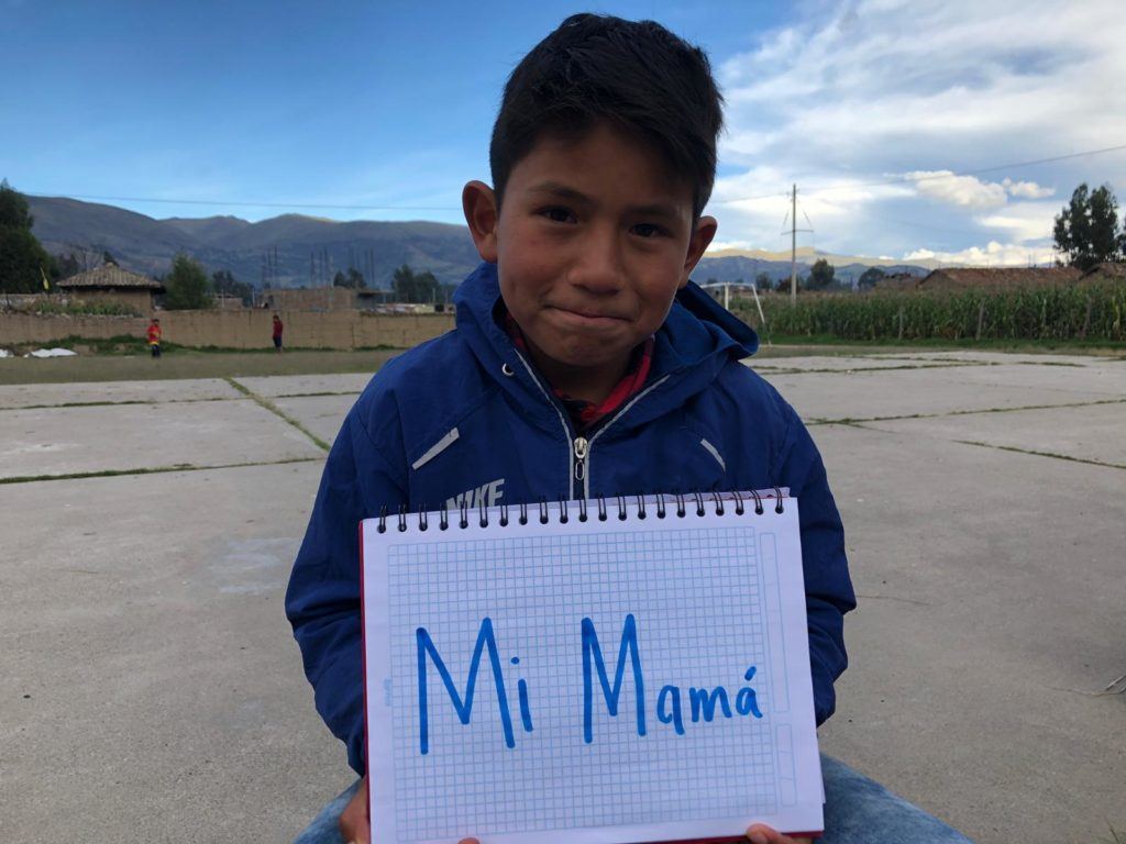 Little boy from peru holding up a sign that shares he is happy for his mom 