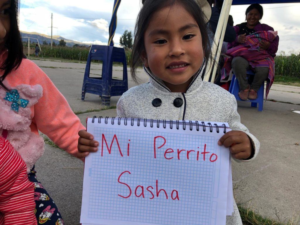 Young girl in Peru shares that her dog Sasha makes her happy. She holds up the words on the white board