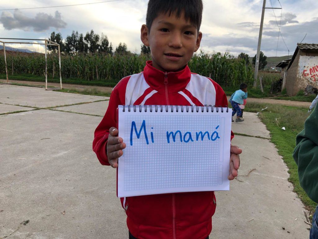 Boy from Peru sharing that his mom makes him happy. His response is written on a notepad