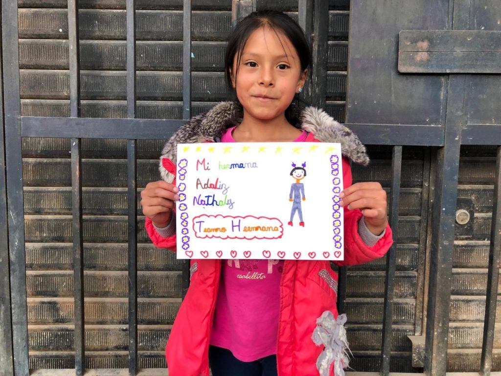 little girl from Peru holding a sign that shares her sister makes her happy 