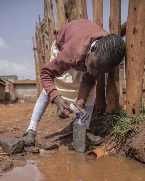 child gathering dirty water in kenya