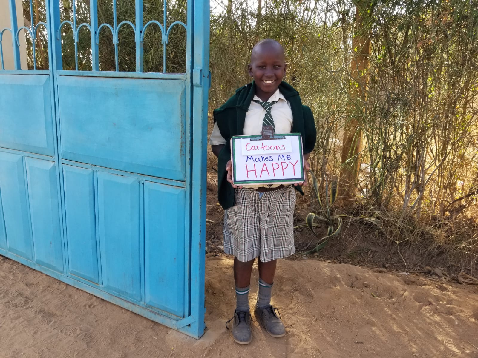 boy stands with sign in front of gate