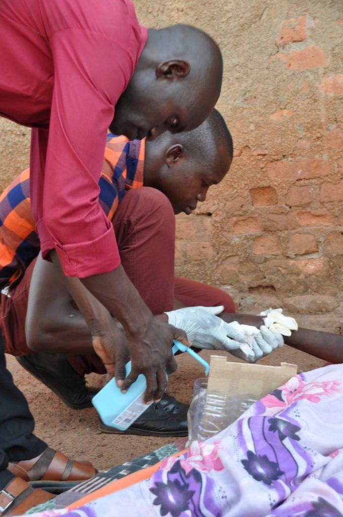 Two students of Dr. Dan Maxwell kneeling beside a patient