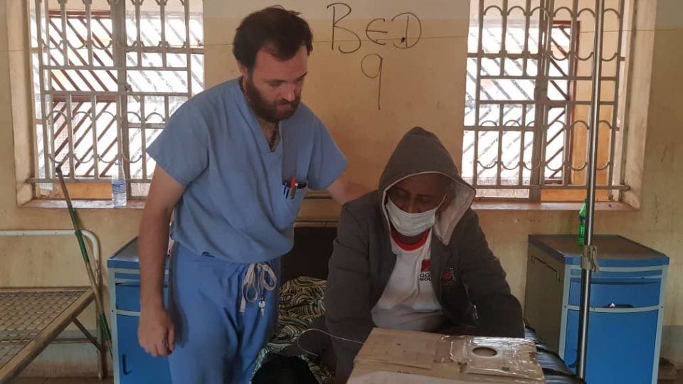 Dr. Dan stands beside a patient sitting down