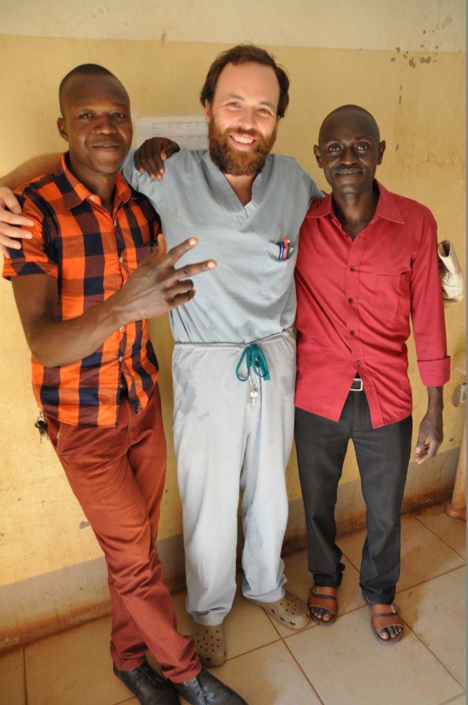 Dr. Dan and two of his students stand against the hospital wall for a photo