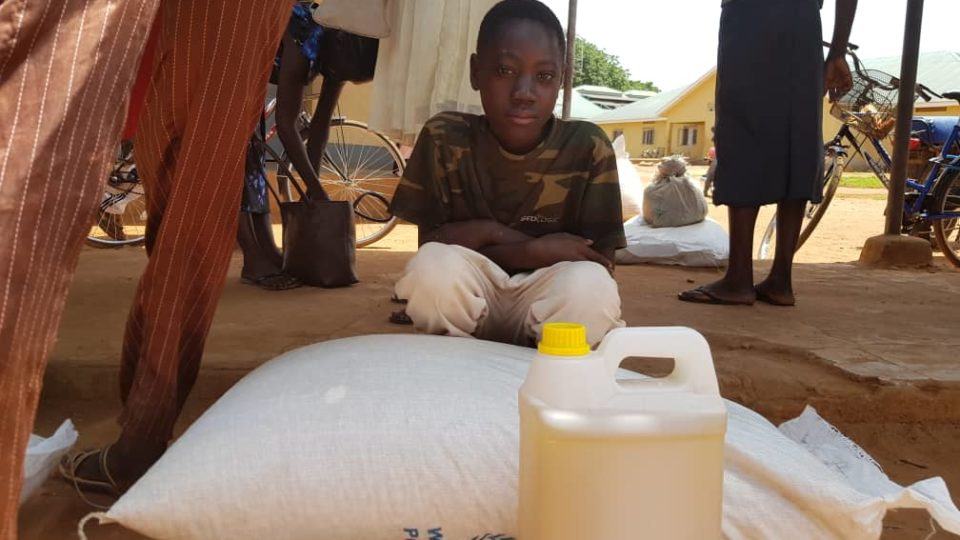 Moses, a young boy served by CMMB, sitting in front of food donation