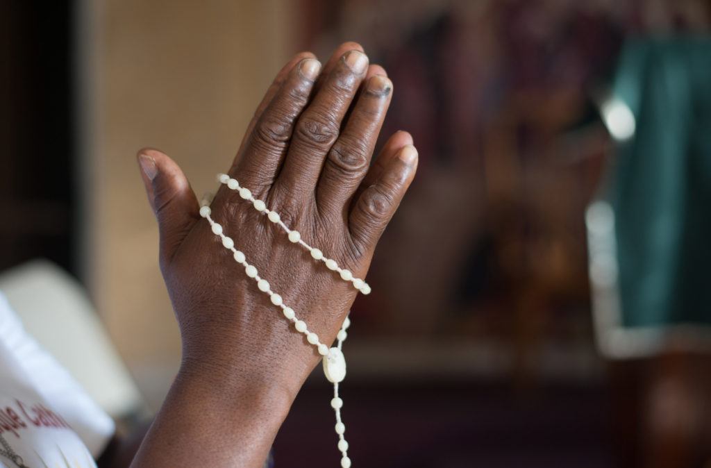 Hands praying around a rosary