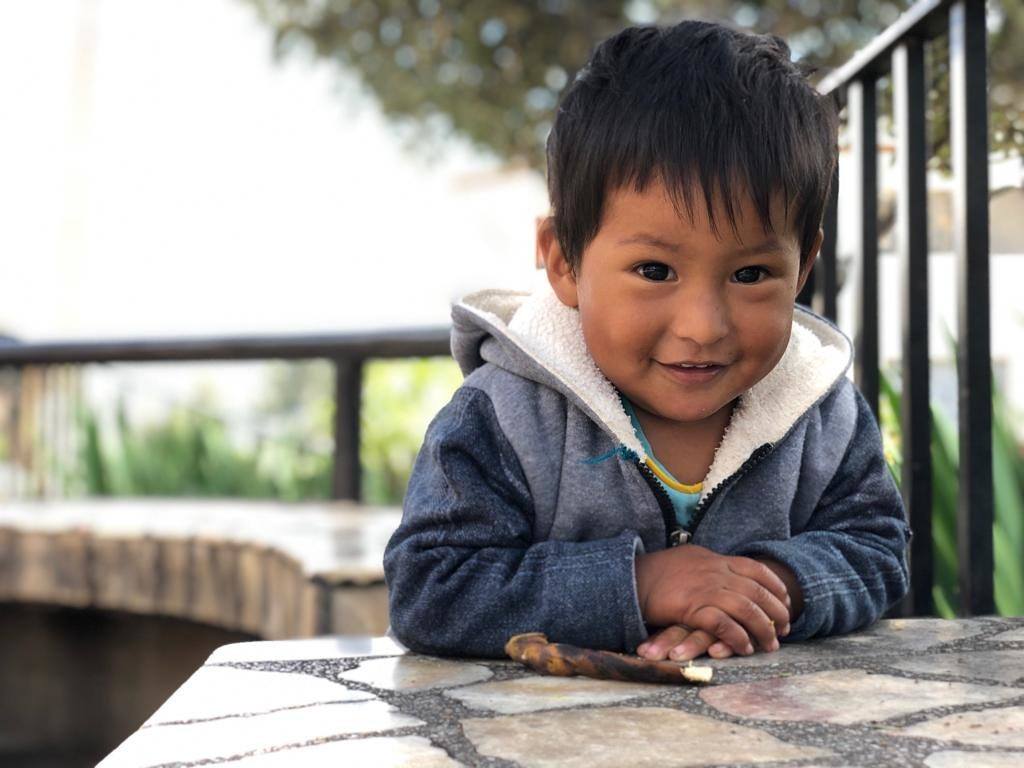 A little boy sits at a table in Peru
