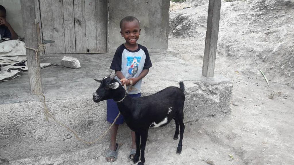 a little boy in Kenya holding the leash for his family goat