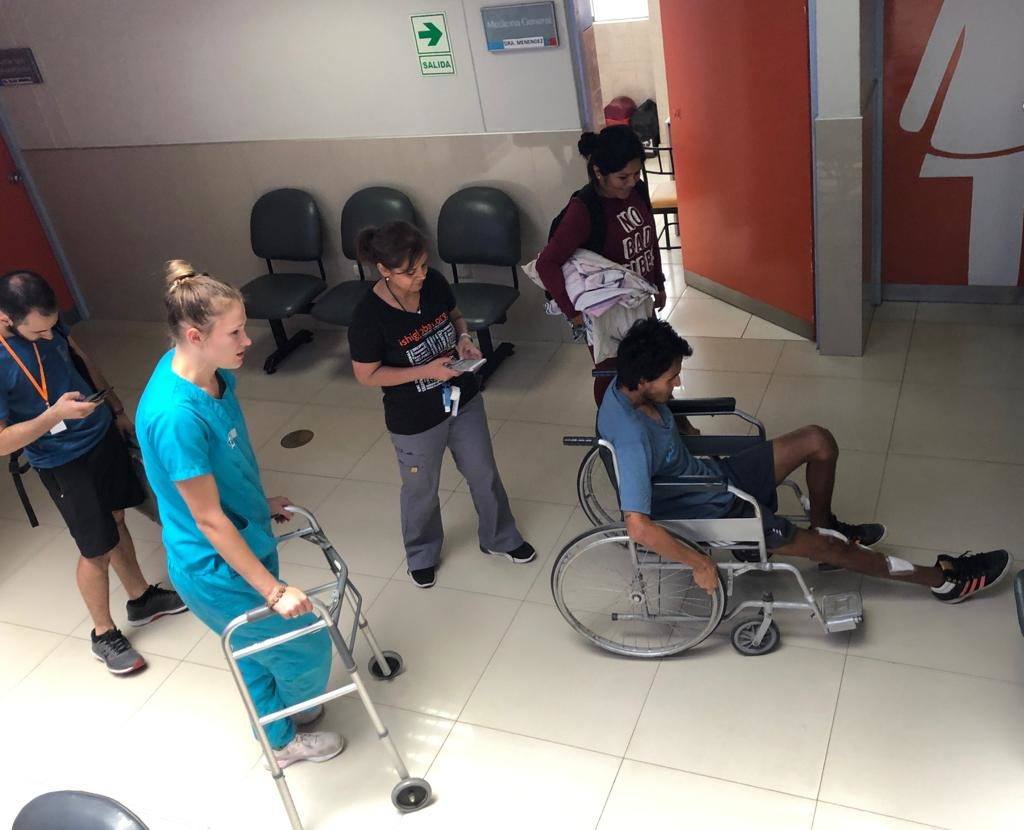 A look at a patient who is being treated by CMMB And the ISHI team. The patient is in a wheelchair and four staff members help him 