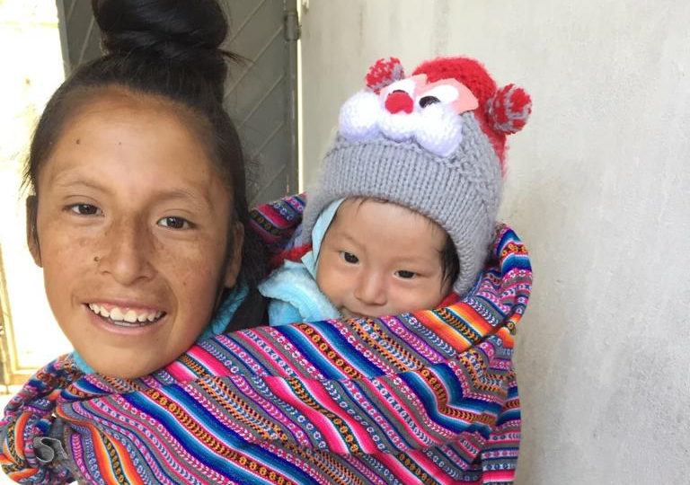 A young mother with her baby in Peru. The mother holds her child on her back