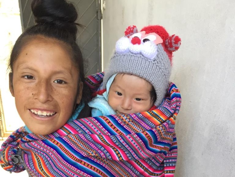 A young mother with her baby in Peru. The mother holds her child on her back