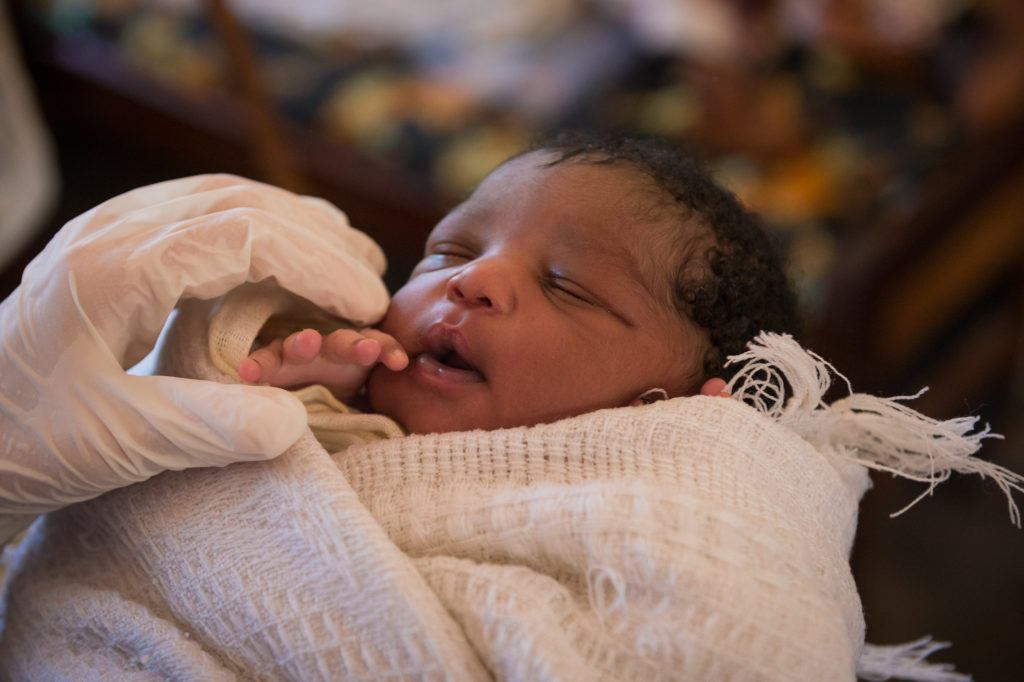 A newborn baby is held by sarah rubino. Only the baby is featured in this image