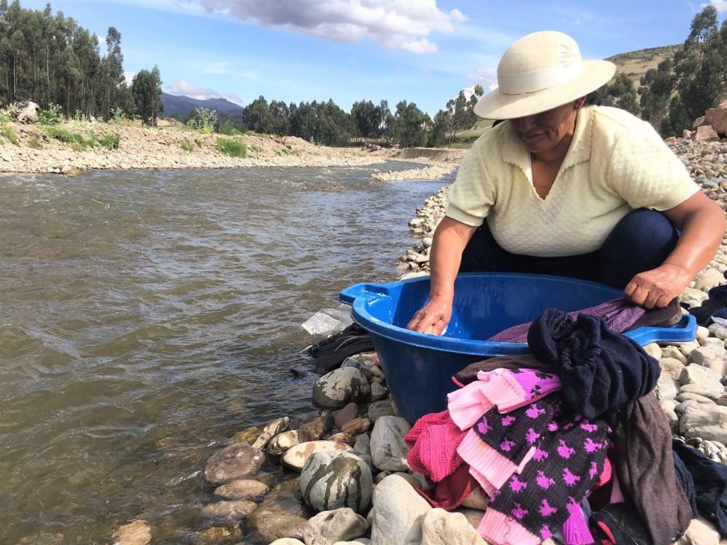 woman washing clothes by the river in tambo huari peru