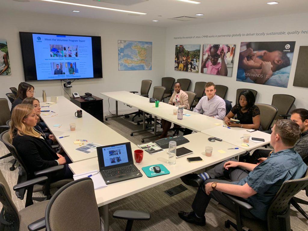 2019 Summer interns learning all about CMMB. They sit together at a conference table for a presentation 